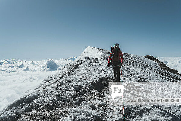 Female mountaineer climbing last meters over ridge towards summit