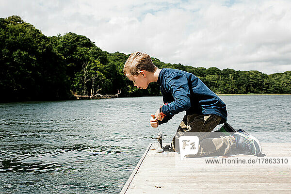 young boy with a fishing crabbing net looking over the dock