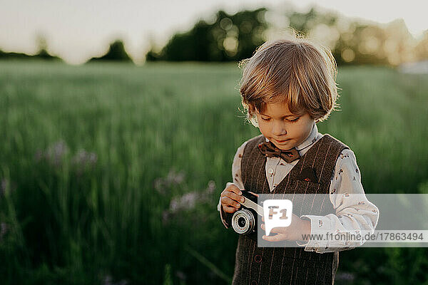 Hipster little boy with vintage camera outdoors. Child in costume