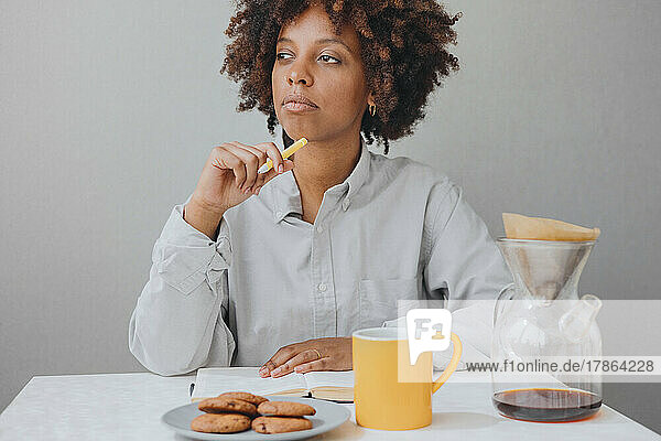 ?urly African-American woman is having breakfast and writing a diary.
