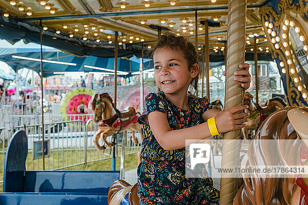 Cute multiracial girl riding on carousel