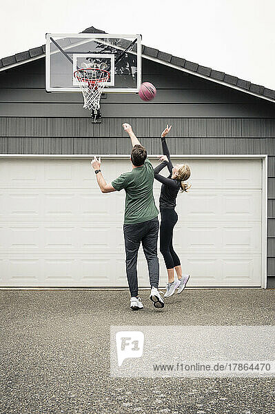 Father and Daughter Practicing Basketball in Driveway at Home