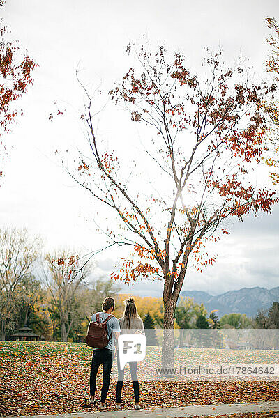 Couple holding eachother outside on an autumn day surrounded by