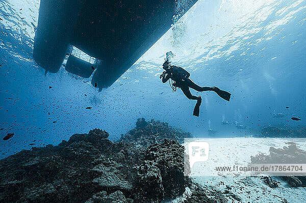 woman diving under dive boat at the Andaman Sea in Thailand