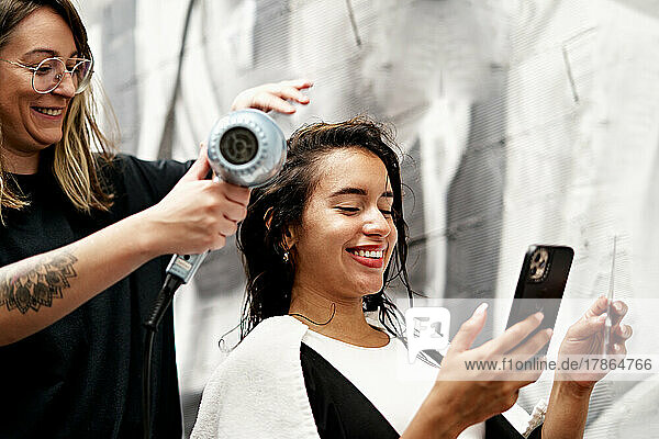 Hairstylist Drying Hair Of Cheerful Customer