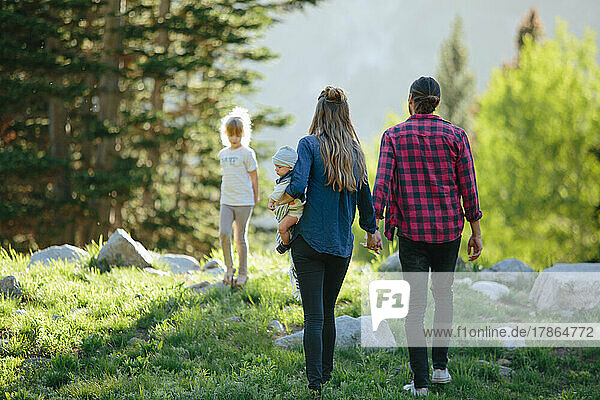 Family holding hands walking in the woods together in Utah mountains