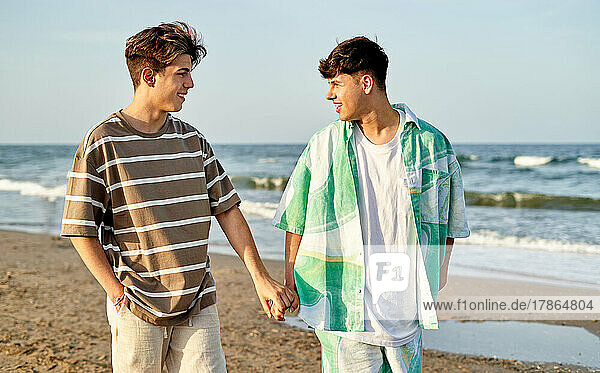 Happy Gay Couple Walking Along The Beach Together