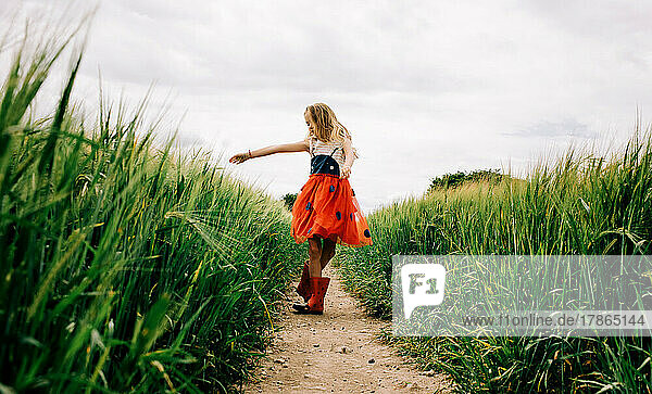 young girl joyfully dancing through corn fields in a bug dress