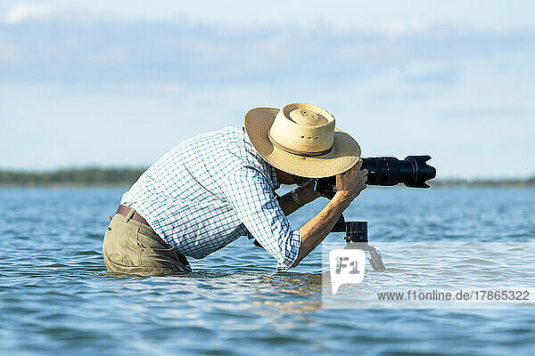 Photographer standing in water taking a photo