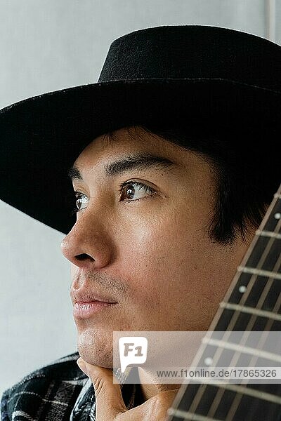 Close up portrait of latin man with the guitar looking away