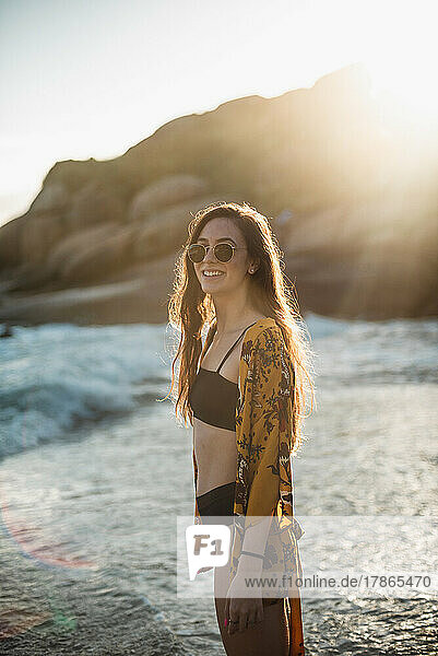 Young woman smiling with sunrise on his back on the beach