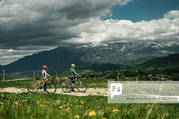 Young couple of cyclists holding their bicycles against mountains