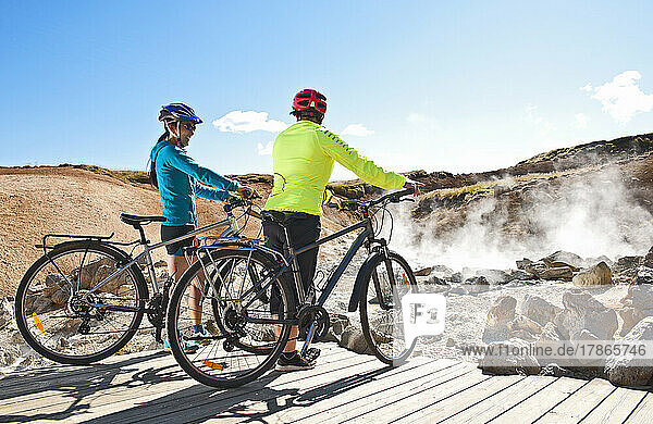 Cyclist looking at geothermal hot spring in Iceland
