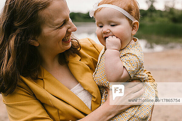 Mother laughs and smiles at red head baby daughter