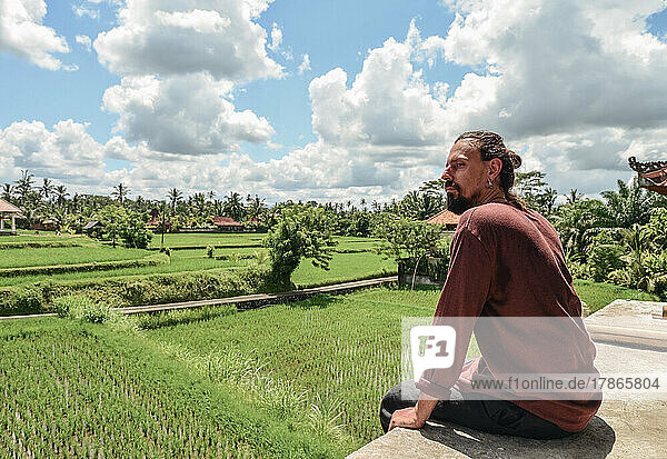 Handsome man with a beard looking at the rice fields
