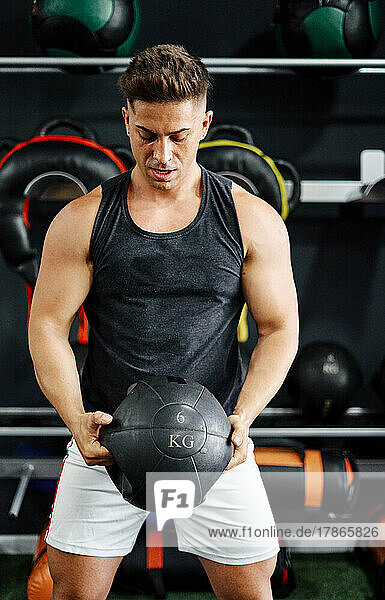 Young and fit man training hard in the gym - Lifting kettlebell
