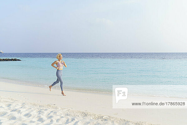 Athletic woman jogging on the beach.