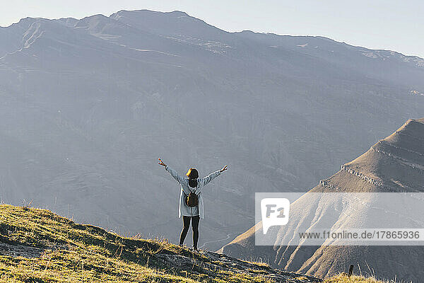 Female hiker standing with outstretched arms in mountain landscape