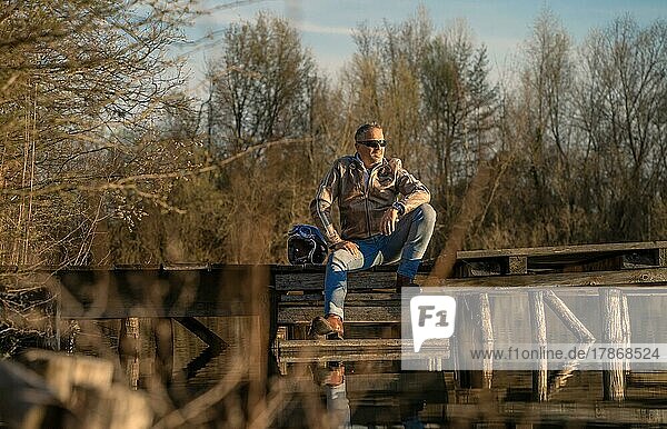 Mann im mittleren Alter sitzt auf einem Steg am See und entspannt. Karlsruhe  Deutschland  Europa