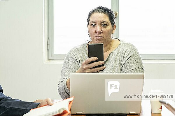 Reife Geschäftsfrau sitzt am Kopf des Tisches in einem Bürobesprechungsraum