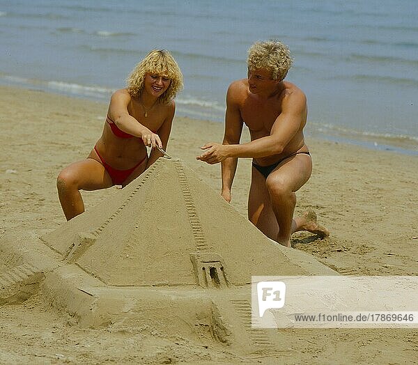 Paar baut Sandburg am Strand  Pyramide Pair builds sand castle on the beach  pyramid