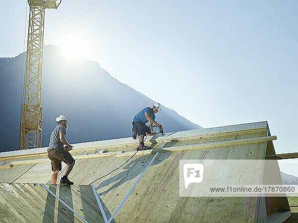 Mitarbeiter installieren Dach mit Bohrmaschine an sonnigem Tag