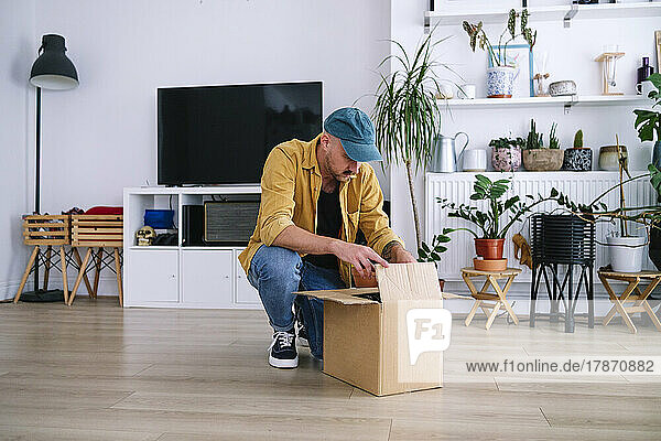 Man opening package in living room at home