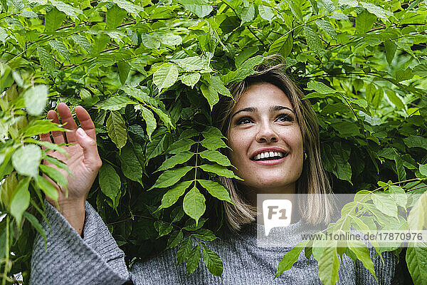 Happy woman amidst green leaves