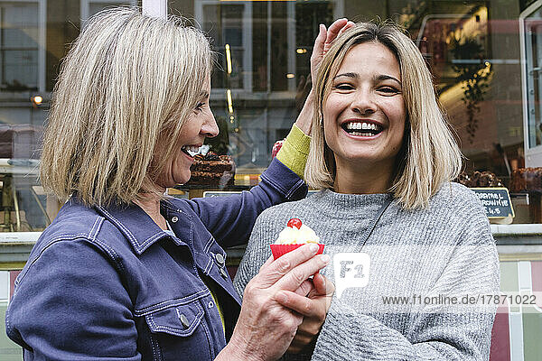 Happy mother and daughter with cupcake outside bakery