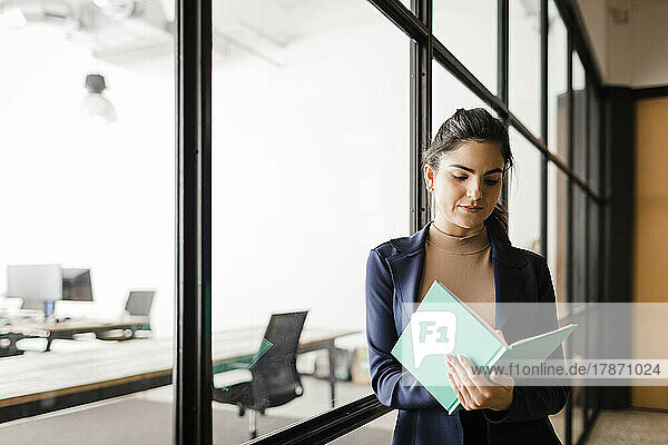 Young businesswoman with diary standing in office