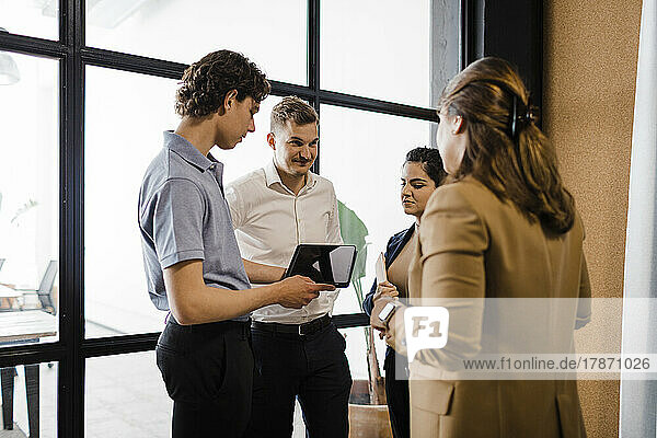 Young businessman with tablet PC having discussion with colleagues in office