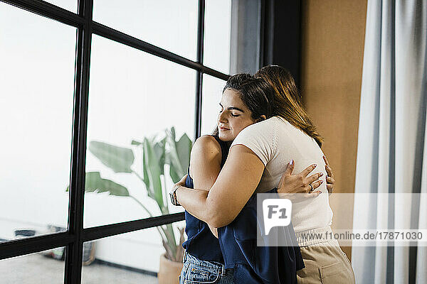 Businesswomen hugging each other in office