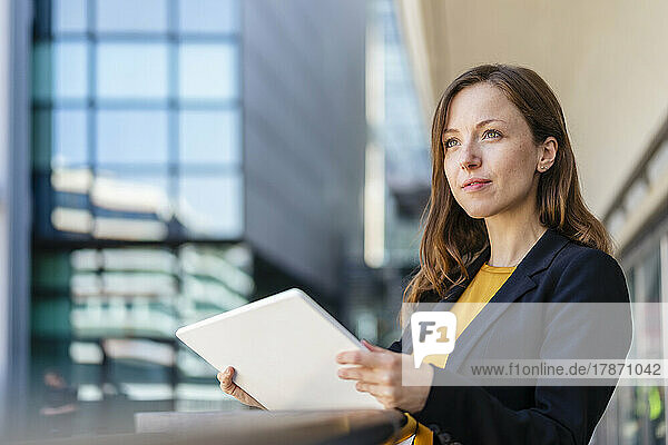 Contemplative businesswoman holding tablet PC