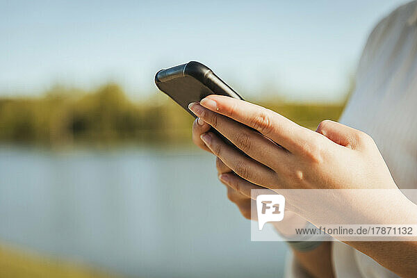 Woman's hand using mobile phone on sunny day