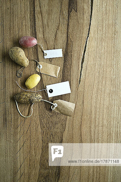 Studio shot of different varieties of labeled potatoes flat laid against wooden background
