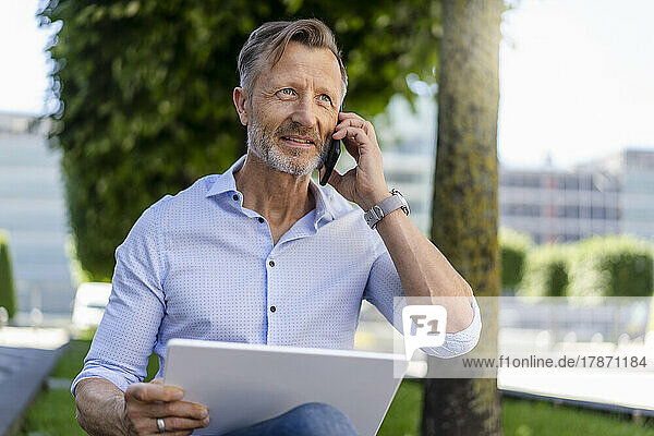 Businessman talking on smart phone holding digital tablet