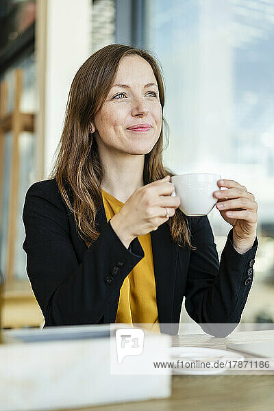 Lächelnde Geschäftsfrau hält Tasse im Café