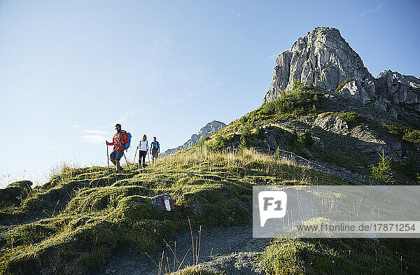 Hikers descending from mountain in front of clear sky  Mutters  Tyrol  Austria