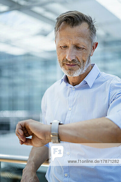 Mature businessman checking time on wristwatch