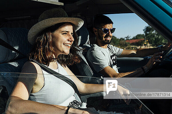Happy woman with man sitting in van on sunny day
