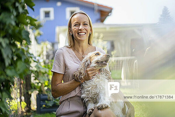 Portrait of smiling woman with dog in garden