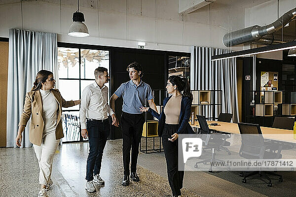 Business colleagues discussing and walking together in modern office