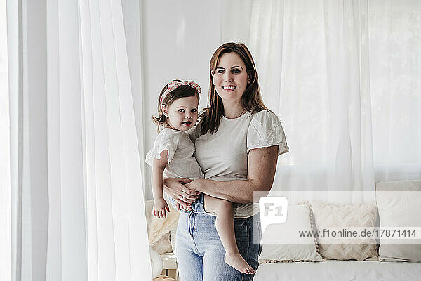 Happy mother and daughter in living room at home