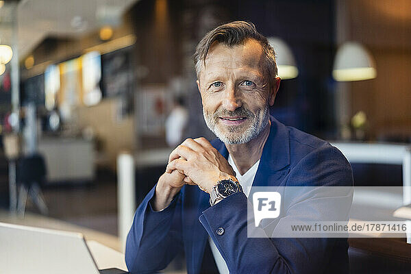 Smiling mature businessman in blazer at cafe