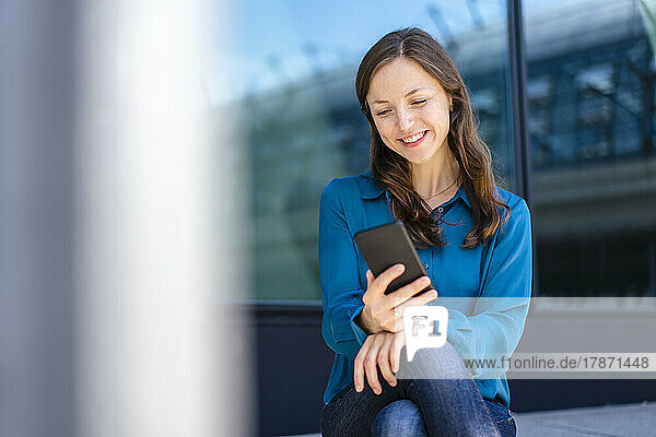 Lächelnde Frau  die Textnachrichten auf dem Mobiltelefon sendet