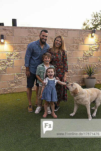 Happy family with dog standing in front of wall