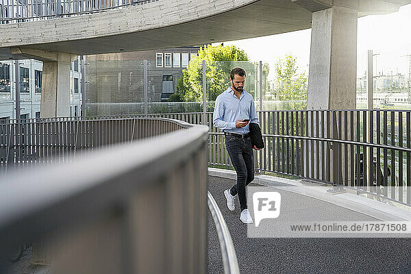 Young businessman using mobile phone at footbridge