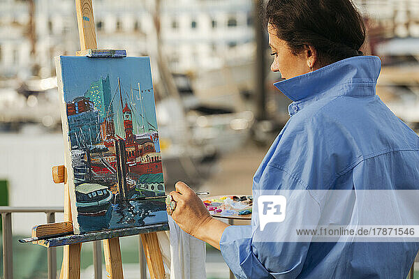 Female painter painting at harbor