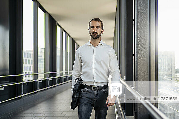 Young businessman with bag walking on elevated walkway