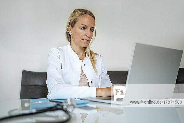 Female doctor using laptop at desk in medical practice